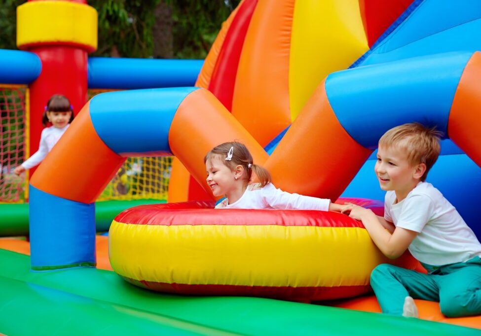 Kids playing in colorful inflatable bounce house.
